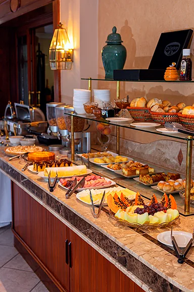 Mesa de café da manhã farta, frutas, pães e a jarra de cerâmica verde
